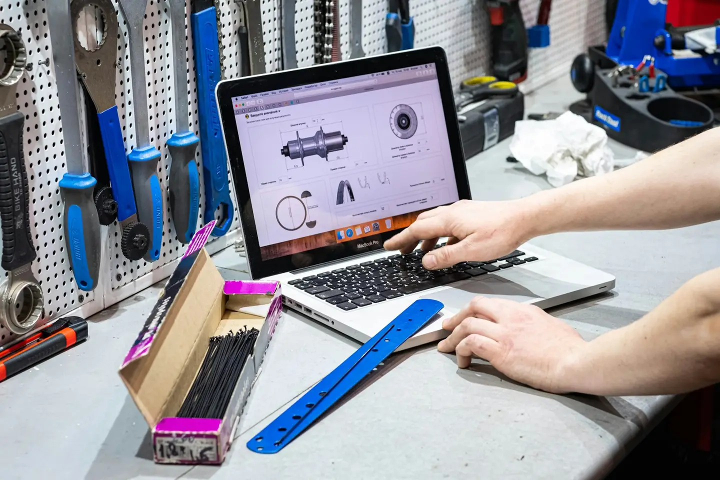 Handwerker arbeitet in seiner Werkstatt an einem Laptop, umgeben von Werkzeug