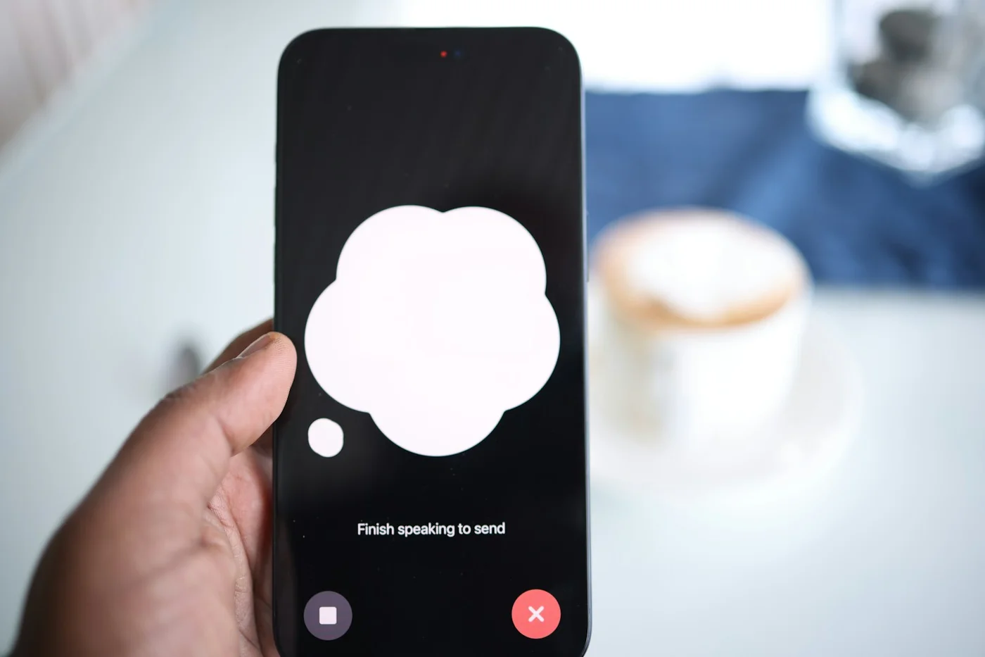 Hand hält ein Smartphone mit geöffnetem KI-Sprachassistenten